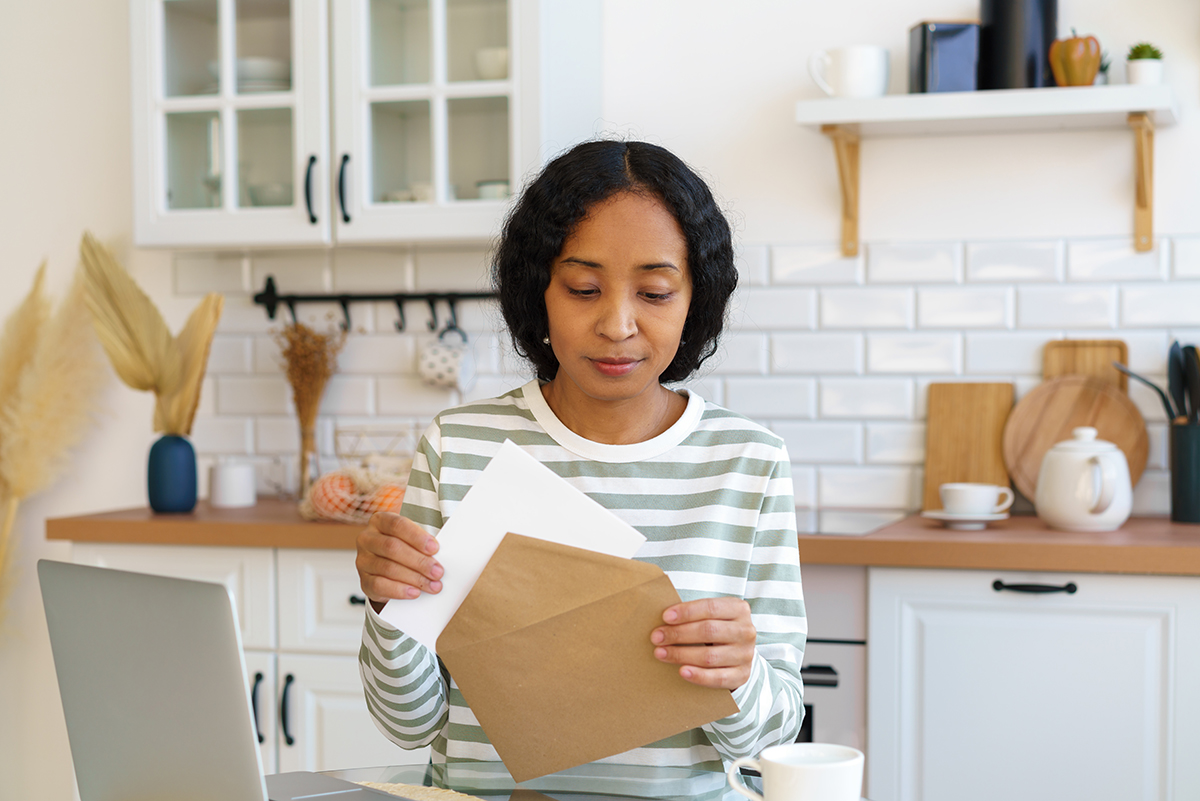 African-american female sending letter. Preparing correspondence for mail delivery. Closing envelope
