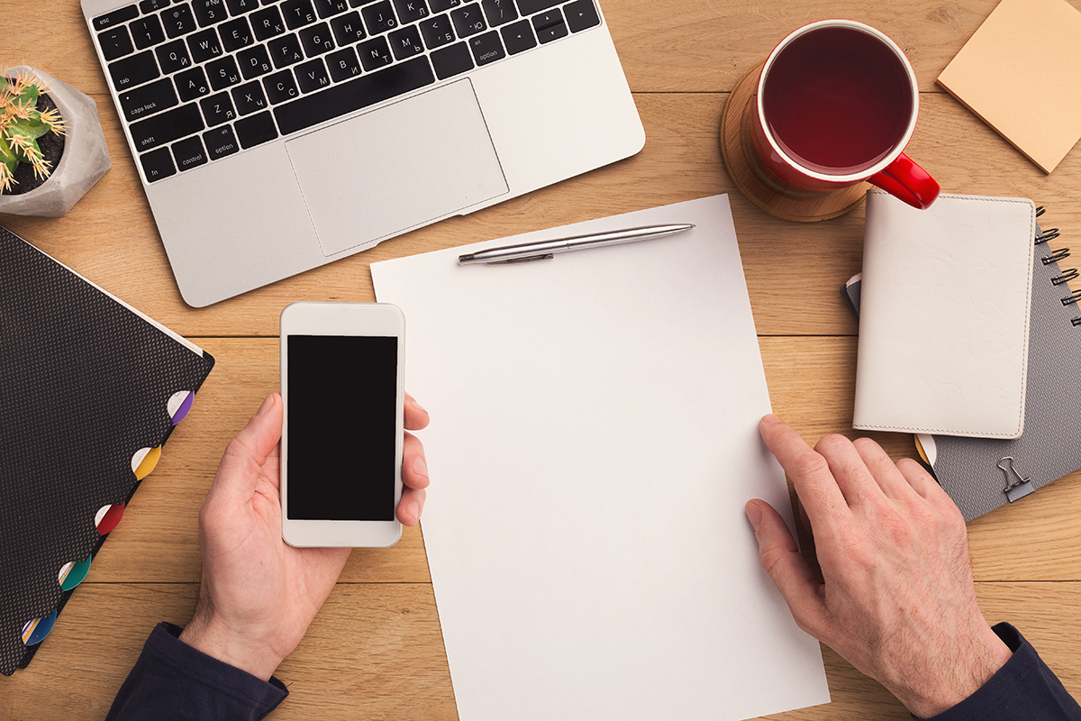 Man writing letter and holding smartphone